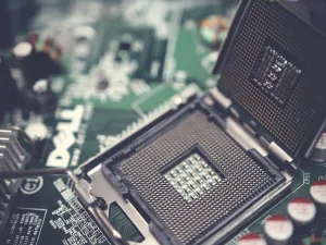 Close-up of an open CPU socket on a motherboard with electronic components and capacitors in the background.