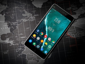 Smartphone with colorful app icons on screen lying on a dark world map background.