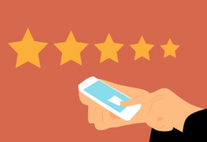 Hand holding smartphone with one star rating selected out of five possible stars against a terracotta background.