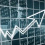 Double exposure of a focused person analyzing financial data with a rising arrow graph overlay indicating stock market growth.