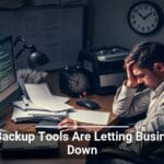 A frustrated individual at a desk with multiple screens displaying code, surrounded by office supplies and clocks, with overlaid text stating 'Data Backup Tools Are Letting Businesses Down'.